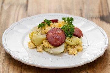 vegetables with egg and smoked sausage on white plate