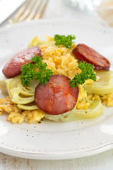 vegetables with egg and smoked sausage on white plate on white background