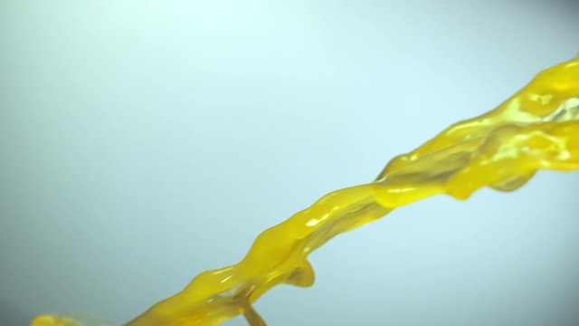 Stream of orange juice, slow motion, color  background