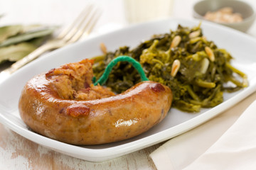 traditional portuguese smoked sausage with turnip greens on white plate on white background