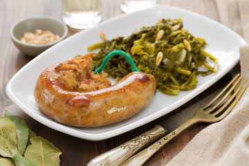 traditional portuguese smoked sausage with turnip greens on white plate