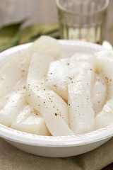 strips of octopus on white dish on brown background