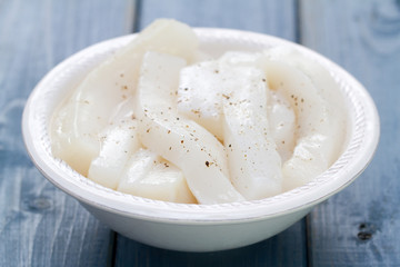 strips of octopus on white dish on blue wooden background