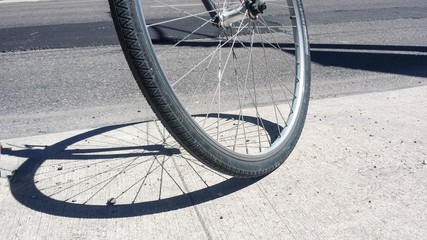 Fototapeta na wymiar Closeup of bicycle wheel with shadow on concrete pavement