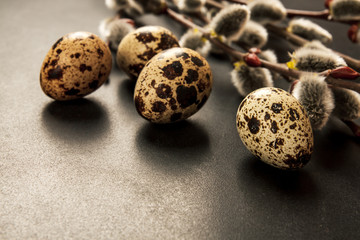 Obraz premium Decorative hand-painted Easter eggs in a nest on a wooden table. willow branches with blossoms. easter themed. Happy Easter