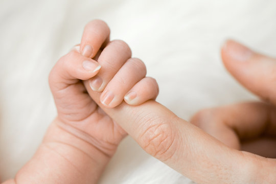 Baby greift nach Finger der Mutter