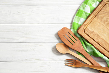 Wooden spoons and other cooking tools with  napkins on the kitchen table.