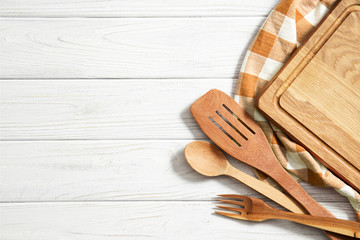 Wooden spoons and other cooking tools with  napkins on the kitchen table.