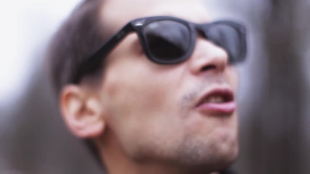 Portrait of young man in sunglasses sing in camera on street. Artist. Singer. Culture. Close up 