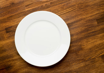 Empty white plate on wooden table top view 