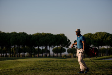 golfer  walking and carrying golf  bag at beautiful sunset