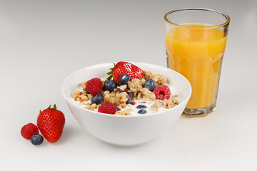 Müsil mit Organgensaft und Milch, Erdbeeren, Heidelbeeren und Himbeeren