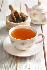 Cup of tea, teapot and dried tea leaves in jute bag