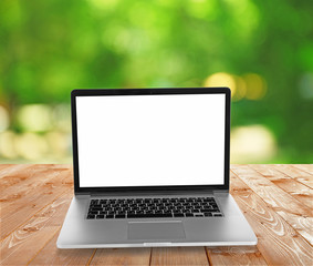 Laptop over wooden table on natural  green blurred background