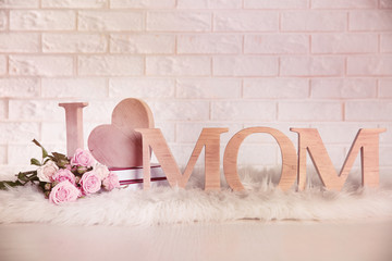 I love mom inscription made of wooden letters with heart on light brick wall background