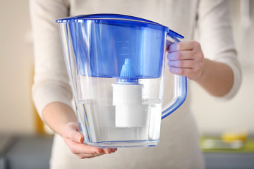 Woman holding water filter jug in the kitchen