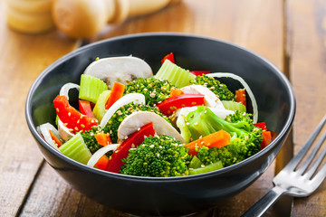 Bowl of healthy vegetarian food. Salad with broccoli, onion, mushroom, carrot and pepper.