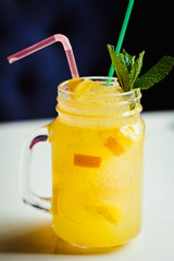 Preparation of the lemonade drink with tubes. Lemonade in the jug with lemons with mint on the table