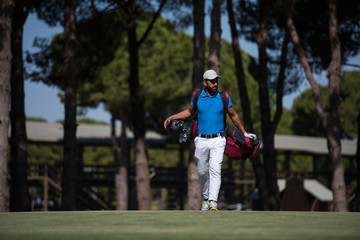 Obraz premium golf player walking and carrying bag