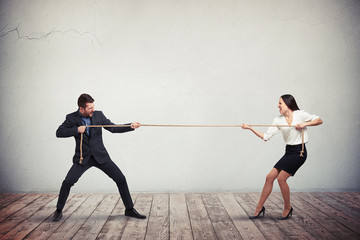 Businessman and businesswoman playing tug of war