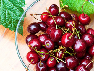 Top view on a Glass bowl full of cherries on the wooden table