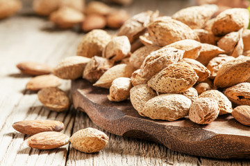 Almonds in shell, vintage wooden background, selective focus