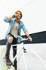 Handsome young man with mobile phone and fixed gear bicycle.