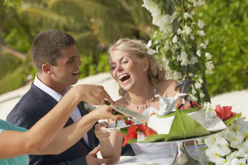 Lovely couple cutting wedding cake during ceremony on tropical i