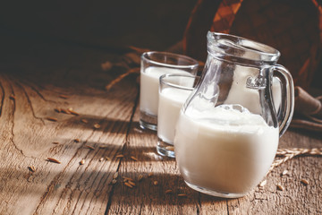 Fresh cow's milk in glass jug, vintage wooden background, still