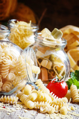 Dry pasta assortment in glass jars for storage, vintage wooden b