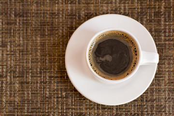 Cup of coffee from top view over wicker texture