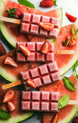 Strawberry watermelon ice cream popsicles with mint over steel tray background