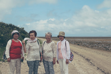 ビーチを歩く高齢者女性4人
