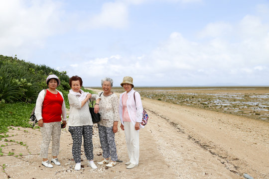 ビーチを歩く高齢者女性4人