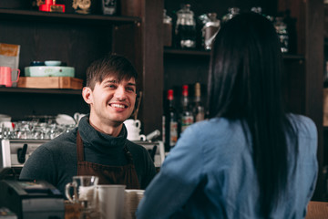 Male cashier smiling for young woman in cafe