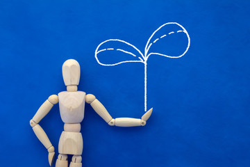 wooden figure on  blue background with drawing of tree eco conce