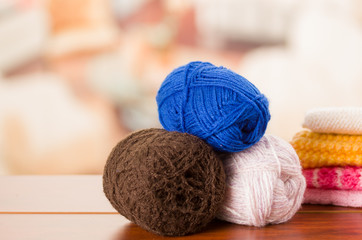 Fototapeta na wymiar Brown, white and blue yarn balls stacked on table desk, blurry background