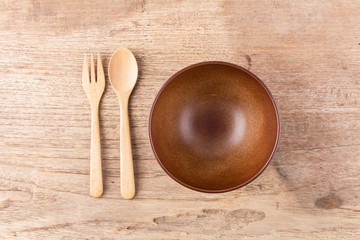 Top view of empty wooden bowl, wooden fork and wooden spoon on w