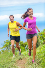Healthy couple athletes trail running in outdoor nature path. Happy young adults training together...