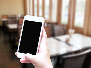 Hand using mobile smartphone in vertical position, blurred backg