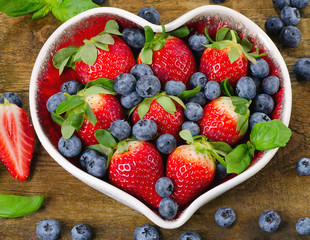 Berries in heart shaped bowl. Healthy eating concept.