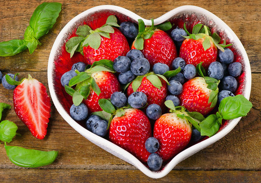 Fresh berries in heart shaped bowl. Healthy food concept.