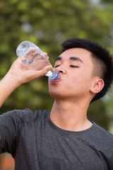 young man or teenager drinking water from bottle