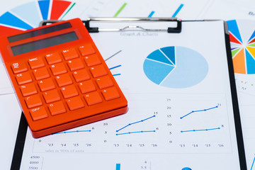 Colorful business charts and calculator with black clipboard