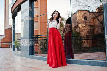 Naklejka premium Portrait of fashionable girl at red evening dress posed backgrou