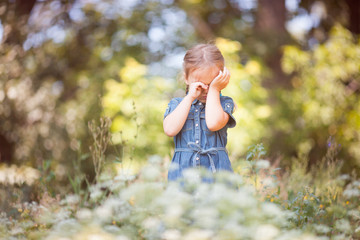 Girl with pigtails in a denim dress. Summer.