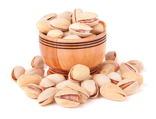 Pistachios pouring out of wooden bowl isolated on white background 