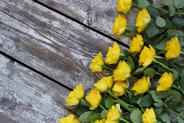 Yellow roses on a wooden background, top view