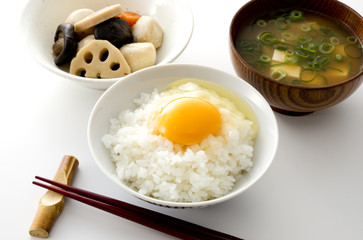 白い背景のみそ汁とたまごかけごはんと煮物と箸