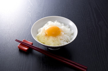 黒木目背景のたまごかけごはんと箸